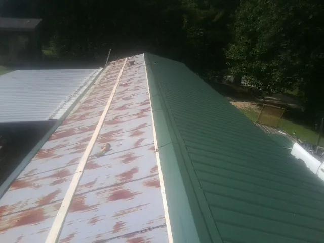 Old rusted panels beside newly installed green metal roofing — Wind Damage Roof Repair by Roofing Brothers in Seminole
