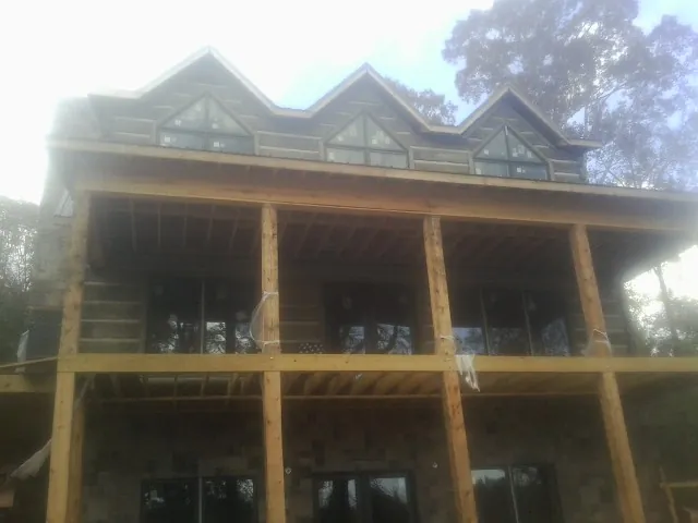 Dormers and porch framing on a large log home under construction — Roof Coating work by our crew in Seminole