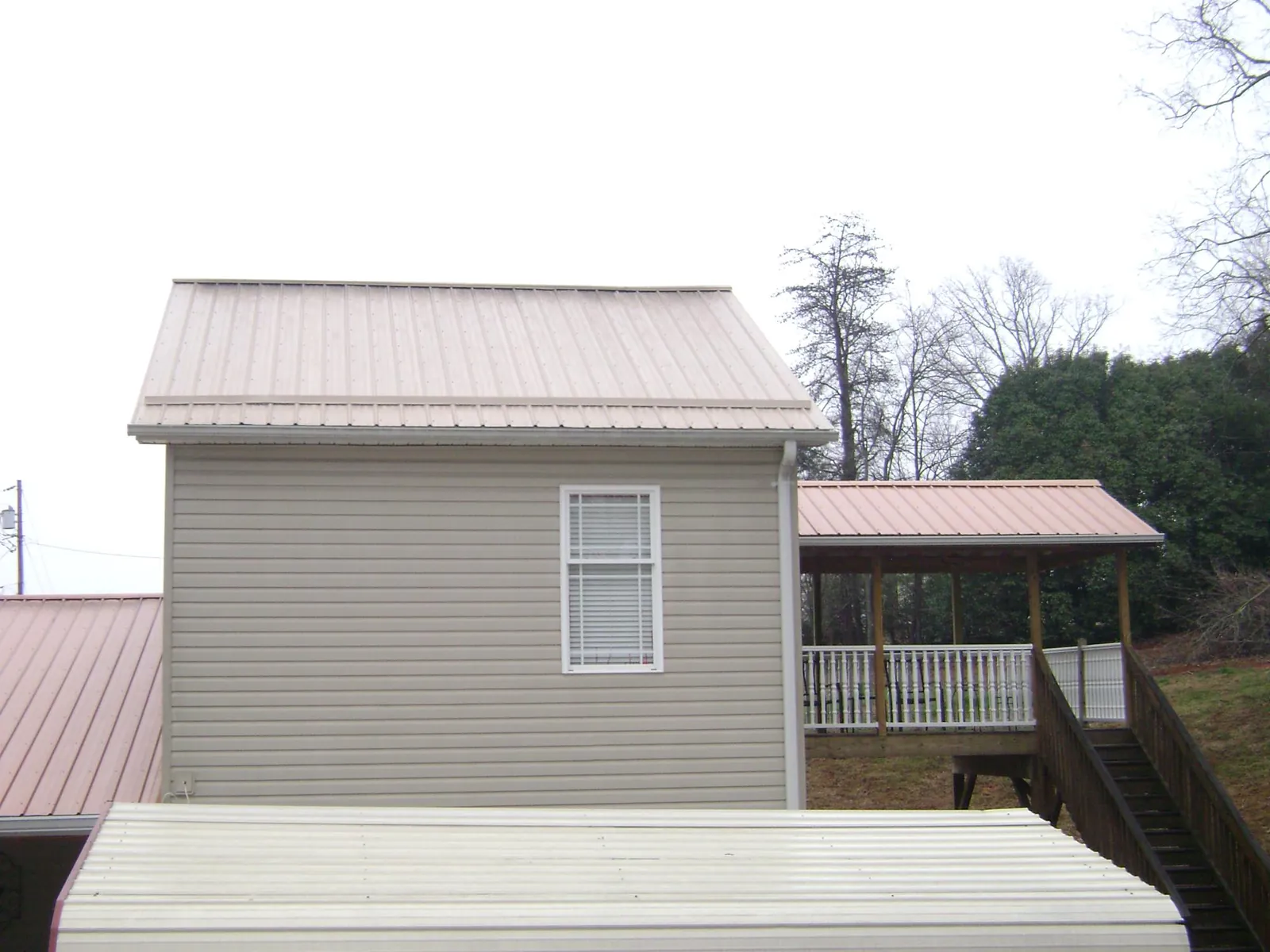 Tan metal roofs on a two story addition and attached porch, from a Roof Replacement job in Seminole